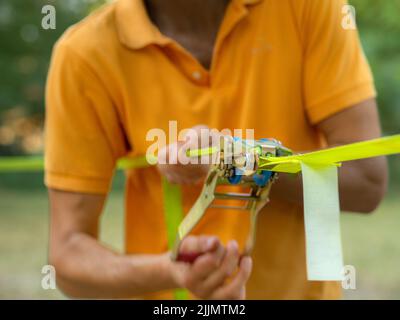 Mindfulness Slackliner Man Crossing a Tightrope in un parco durante un tramonto soleggiato. Foto Stock