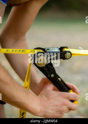 Mindfulness Slackliner Man Crossing a Tightrope in un parco durante un tramonto soleggiato. Foto Stock