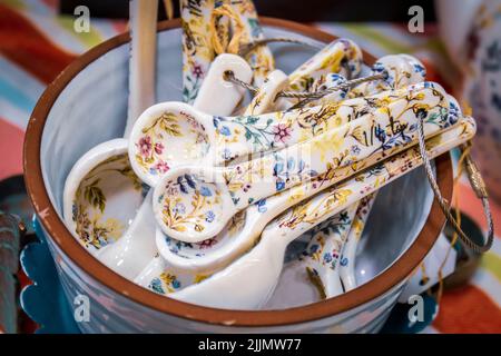 Primo piano dei cucchiai di misurazione in ceramica con stampa floreale in esposizione nel contenitore delle stoviglie - fuoco selettivo. Foto Stock