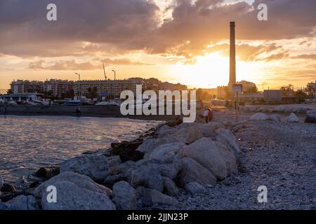 Una vista panoramica del sole che si nasconde dietro gli edifici della città durante il tramonto Foto Stock