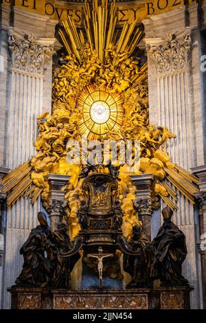 L'abside della Basilica di San Pietro in primo piano con la luce dorata di un sole mattutino che illumina la finestra di vetro colorato che mostra la colomba che rappresenta Go Foto Stock