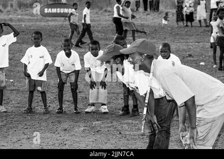 Una scala di grigi di bambini africani che svolgono attività legate al calcio nel campo scolastico di Johannesburg, Sudafrica Foto Stock