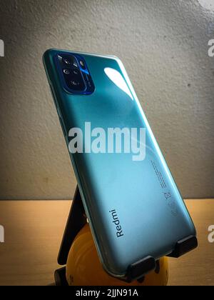 Primo piano di Xiaomi Redmi Note 10 in colore verde lago su un supporto mobile sulla scrivania Foto Stock