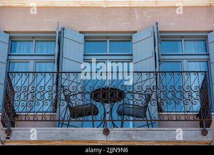 tavolo e due sedie su un balcone di ferro arrough ornato sull'isola di creta in grecia, balcone con tavolo per due al sole estivo. Foto Stock