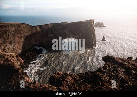Una vista panoramica della penisola di dyrholaey contro il cielo blu nella luce del sole nel sud dell'Islanda Foto Stock