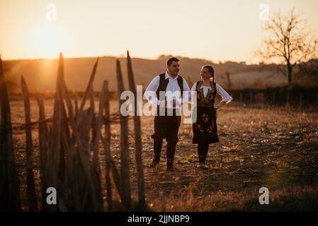 Un primo piano di una giovane coppia serba in costume tradizionale sul campo Foto Stock