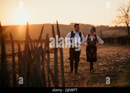 Un primo piano di una giovane coppia serba in costume tradizionale sul campo Foto Stock