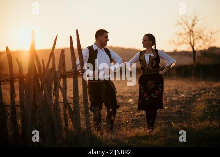 Un primo piano di una giovane coppia serba in costume tradizionale sul campo Foto Stock