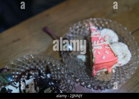 Una vista dall'alto di torte di sapori diversi su piatti di vetro su un tavolo di legno con sfondo sfocato Foto Stock