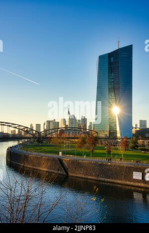 Un colpo verticale del sole che brilla attraverso la Banca Centrale europea sullo sfondo del cielo. Foto Stock