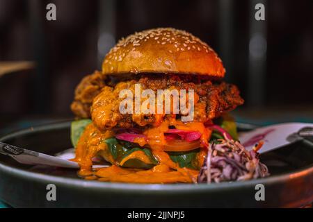 Un primo shot di hamburger di pollo in un ambiente ristorante scuri e grungy Foto Stock