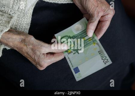 Le mani femminili tengono cento euro. Pensione, povertà, problemi sociali e il tema della vecchiaia. Foto Stock