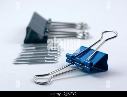 Un primo piano di una clip di carta blu per rilegatori metallici, isolata su sfondo bianco Foto Stock