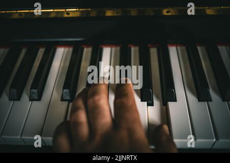 Un primo piano di una mano sui tasti del pianoforte che suonano musica incredibile Foto Stock