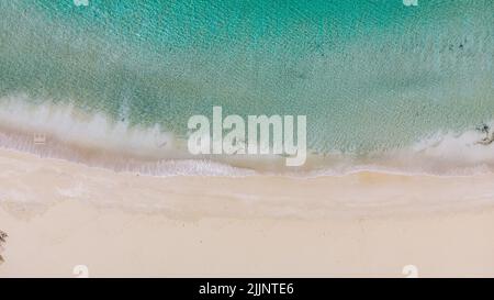 Un'immagine aerea di onde morbide dell'oceano con schiuma su una spiaggia sabbiosa a Little Bay, Tortola, Isole Vergini britanniche Foto Stock