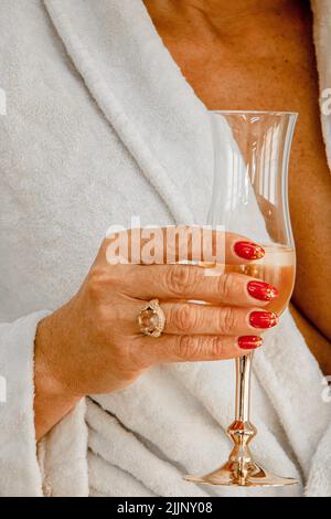Un primo piano verticale di una donna di mezza età che tiene un bicchiere in bagno kimono Foto Stock