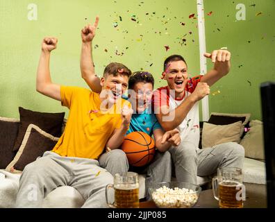 Tre appassionati di basket maschi che guardano la partita Foto Stock