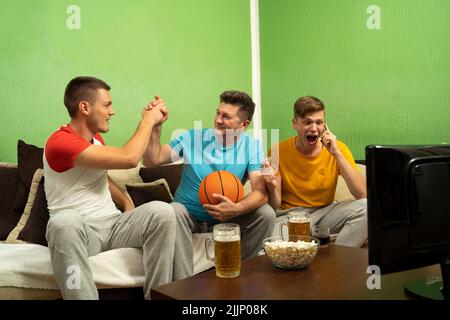 Tre appassionati di basket maschi che guardano la partita Foto Stock