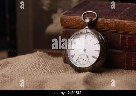 Un vecchio orologio da tasca e libri antichi Foto Stock