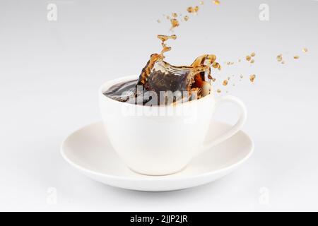 Un caffè che fuoriesce da una tazza isolata su sfondo bianco. Foto Stock