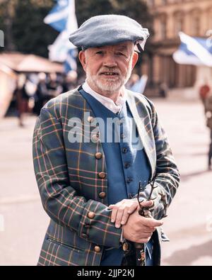 Primo piano di un uomo scozzese anziano che indossa una giacca e un cappello in tartan a Glasgow, Regno Unito Foto Stock