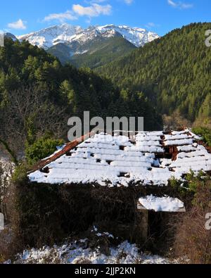 Una vista verticale del tetto innevato di una vecchia casa in montagna nel villaggio di Zarouchla nel sud della Grecia Foto Stock