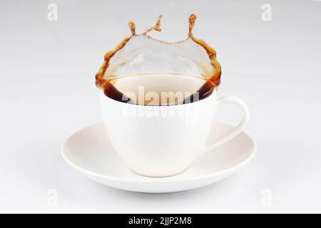 Un caffè che fuoriesce da una tazza isolata su sfondo bianco. Foto Stock