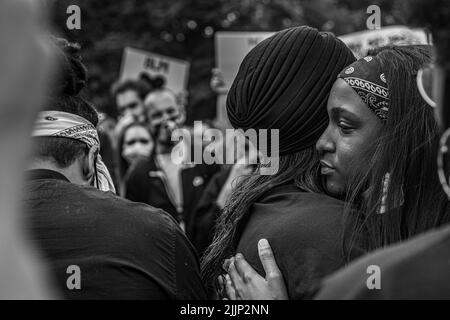 Un colpo in scala di grigi di due femmine che abbraccia Black Lives Matter protesta, Glasgow Green. REGNO UNITO Foto Stock