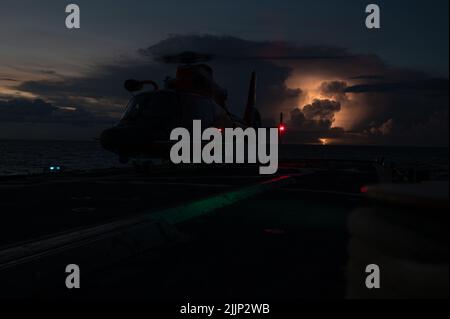 Un Delfino MH-65 della Guardia Costiera degli Stati Uniti, un bene della Guardia Costiera Helicopter Interdiction Tactical Squadron (HITRON), atterra sul ponte di volo dell'orso USCGC (WMEC 901) durante le esercitazioni di qualificazione di atterraggio del ponte, Oceano Atlantico, 12 luglio 2022. Le qualifiche per l'atterraggio sul ponte consentono sia all'equipaggio di bordo che all'equipaggio di addestrare con successo il personale per l'atterraggio di un elicottero a bordo di una nave. (STATI UNITI Foto della Guardia Costiera di Petty ufficiale 3rd Classe Matthew Abban) Foto Stock