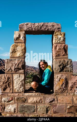 Una donna seduta sulle pietre allineate tra loro in forma architettonica Foto Stock