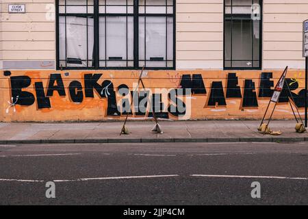 Il testo "Black Lives Matter" scritto su un muro arancione, Glasgow, Regno Unito Foto Stock