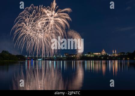 Una bella vista dei fuochi d'artificio nel cielo notturno sul lago vicino alla città Foto Stock