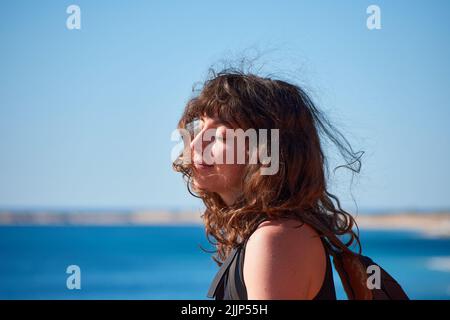 Un fuoco poco profondo di una bella donna sorridente brunetta caucasica contro il cielo blu Foto Stock