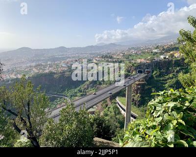 Una vista aerea attraverso il verde del ponte con auto che attraversano il tunnel Foto Stock