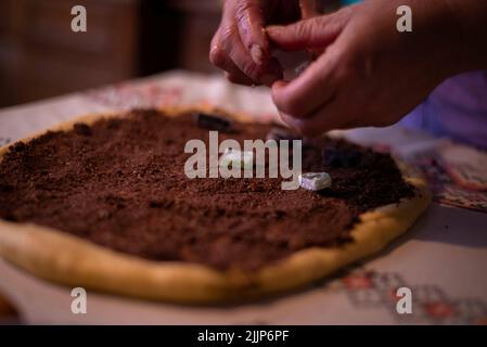 Una casalinga che aggiunge il ripieno all'impasto Foto Stock