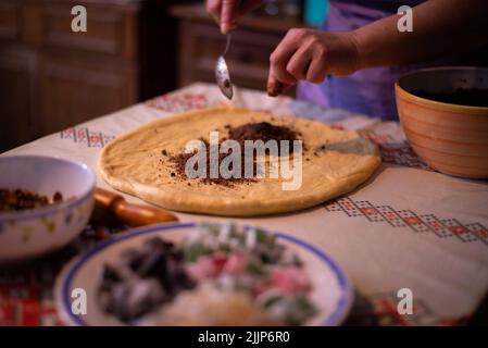 Una casalinga che aggiunge il ripieno all'impasto Foto Stock