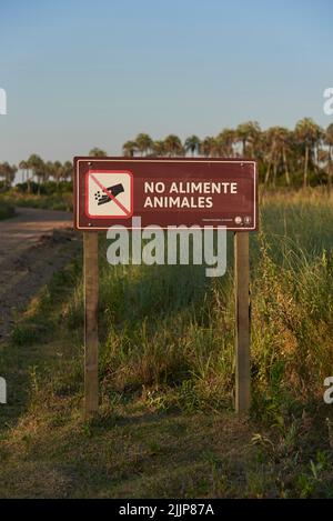 31 dicembre 2021, Parco Nazionale El Palmar, Entre Rios, Argentina: Segno sul lato di una strada sterrata con il messaggio non dare da mangiare agli animali Concepti: ecologica Foto Stock