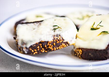 Primo piano di un piatto di pane di segale con formaggio fuso e timo fresco Foto Stock