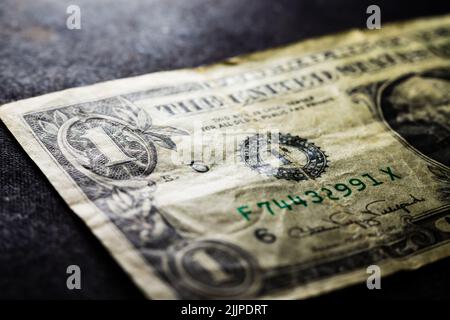 Primo piano della banconota da un dollaro sminuzzata sulla superficie nera Foto Stock