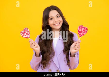 Ragazza adolescente con caramelle al caramello sui bastoni, dolce dipendenza da zucchero. Bambino con lollipops. Adolescente felice, emozioni positive e sorridenti di ragazza teen. Foto Stock