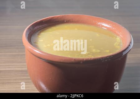 Zuppa gialla in una ciotola di argilla, la zuppa è su un tavolo di legno con spazio copia e cucchiaio. Foto Stock