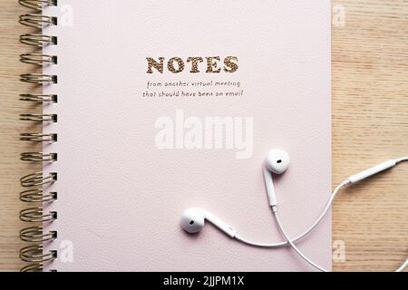 Notebook appoggiato sul tavolo con cuffie bianche, rosa, accessori per ufficio Foto Stock