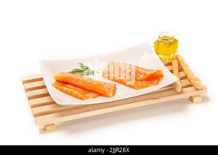 Un primo piano di sushi di salmone con rosmarino su un piatto bianco Foto Stock