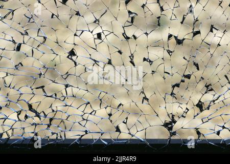 Le splendide linee nere e argentate di una finestra frantumata creano un motivo intricato nel vetro. Foto Stock