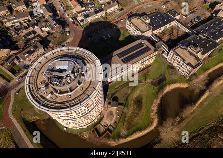 Area urbana aerea che mostra una torre rotonda colorata e edifici laterali con un'ombra aspra Foto Stock