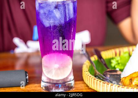 Bevanda a base di erbe dal fiore porpora asiatico di pig-onwing, servita in un bicchiere con freddo rinfrescante Foto Stock