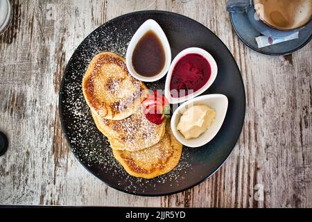 Una vista dall'alto di pancake dolci su un piatto con marmellata e salse in ciotole Foto Stock