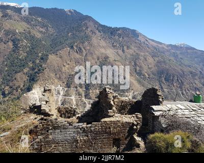 Le rovine della casa di 52 camere nel villaggio di Darkot, Uttarakhand, India con montagne sullo sfondo Foto Stock