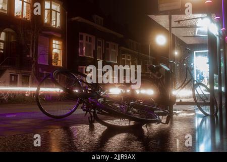 Le biciclette parcheggiate all'aperto vicino alla fermata dell'autobus di notte Foto Stock