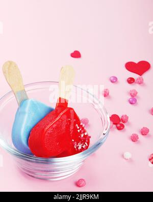 Diversi tipi di gelato a forma di popsicle su sfondo rosa. Atmosfera estiva. Foto Stock